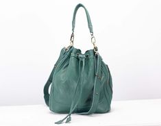 "The Danae bucket bag in pebbled petrol green soft Italian cow leather. It is fully lined with floral cotton fabric. Easy to wear and very comfortable to carry. A medium-sized drawstring bag ideal for when you are on the go. It has a soft silhouette with a structured base and it features two types of handles. A short handle and a long adjustable strap, both detachable. The two exterior side zippered pockets are very handy for your phone, glasses, or anything else you want to have quick access to Luxury Green Crossbody Bucket Bag, Cheap Green Bucket Bag For Travel, Cheap Green Bucket Bag For Women, Cheap Chic Green Bucket Bag, Affordable Green Handheld Bucket Bag, Cheap Green Shoulder Bucket Bag, Cheap Green Bucket Bag With Main Compartment, Cheap Green Bucket Bag With Single Compartment, Cheap Green Bucket Bag