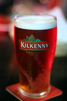 a glass of beer sitting on top of a red coaster