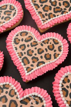 decorated cookies in the shape of hearts with pink icing and leopard print on them