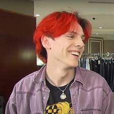 a young man with red hair is smiling