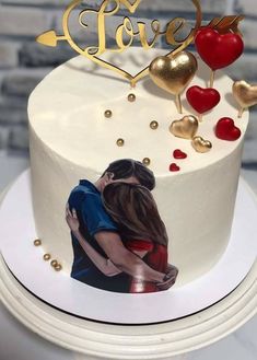 a white cake with gold lettering and hearts on it, sitting on top of a table