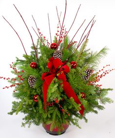 a christmas arrangement with pine cones and red ribbon