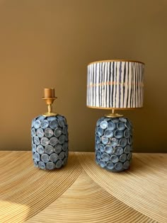 two blue vases sitting next to each other on top of a wooden table with a lamp