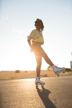 a person riding a skateboard on a street with the sun shining behind them and grass in the foreground