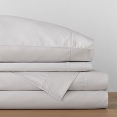 a stack of white sheets and pillows on a wooden floor