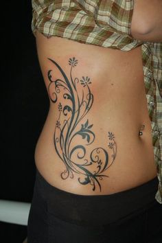 a woman's stomach with an artistic tattoo design on her belly and lower back