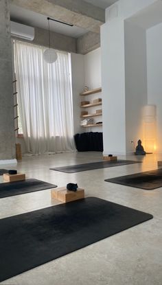 yoga mats are arranged on the floor in front of a large window with sheer curtains