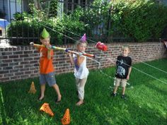 three children are playing in the yard with plastic toys and hats on their heads,