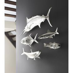 five metal fish mounted on the wall in a room with black and white walls,