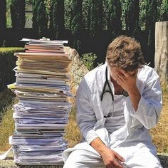 a man sitting on the ground next to a pile of papers with a stethoscope in his hand