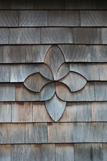 a metal flower on the side of a wooden building with no leaves or flowers in it