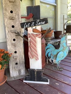 a wooden sign that says let it snow on top of a porch next to flowers