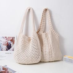 two crocheted purses sitting on top of a white table next to photos