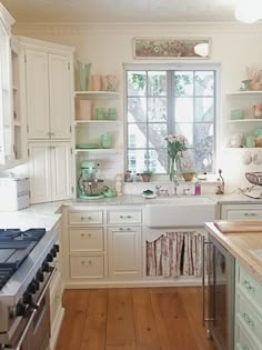 a kitchen filled with lots of white cabinets and counter top space next to a window