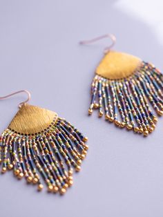 Embrace the celebration with the Confetti Fringe earrings! Each strand showcases a kaleidoscope of colors (blue, green, purple, pink), arranged in a playful confetti-like pattern. Adorning the ends of the fringe are shimmery gold drop beads. Draping from a brass fan shape, these earrings strike a balance between sophistication and bohemian charm. Their lively hues combine with captivating movement, making them a perfect choice for when you’re feeling carefree and spirited. Materials - Miyuki gla Rainbow Party Jewelry With Dangling Beads, Multicolor Bohemian Chandelier Earrings For Celebrations, Bohemian Multicolor Chandelier Earrings For Celebrations, Rainbow Dangle Tassel Earrings Gift, Rainbow Dangling Beads Earrings For Party, Multicolor Dangling Beads Earrings For Celebration, Multicolor Dangle Chandelier Earrings For Celebration, Multicolor Festive Jewelry With Ear Wire, Multicolor Dangle Earrings For Celebration