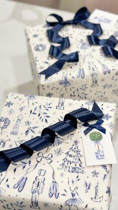 two wrapped gift boxes with blue bows on them sitting on a counter top next to each other