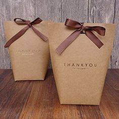 two brown paper bags with ribbon tied around the top and thank you written on them