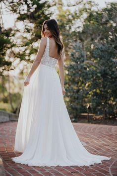 a woman in a wedding dress standing on a brick walkway