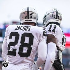 two football players standing next to each other on a field with their arms around each other