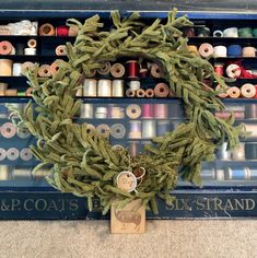 a wreath made out of yarn and spools of thread sitting on top of a shelf