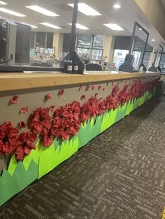 some red flowers are on the side of a green and gray wall in an office