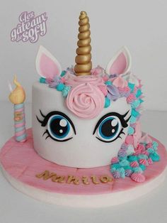 a white cake with pink frosting and a unicorn's head on top