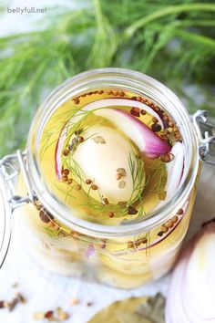 a jar filled with food sitting on top of a table next to garlic and herbs