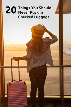 a woman standing in front of an airport window with her luggage and looking out the window