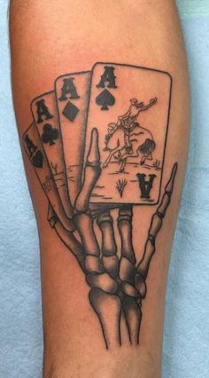 a tattoo on the leg of a man with four playing cards in his hand and two hands holding each other