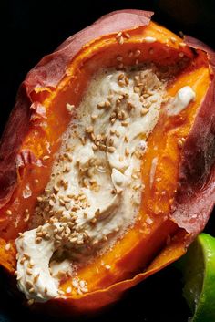 the inside of a stuffed pepper with cream and nuts on top, next to a lime