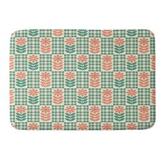 a green and pink flower pattern on a white background bath mat with an orange flower in the center