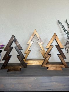 three wooden christmas trees sitting on top of a table next to a potted plant