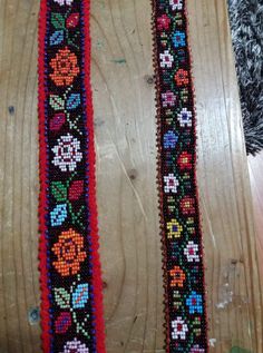 two colorful beaded bracelets sitting on top of a wooden table next to each other