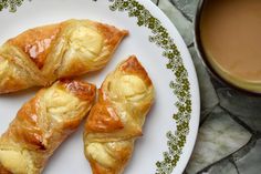 three croissants on a plate next to a cup of coffee