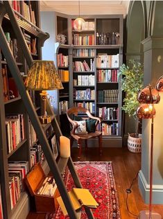 a living room filled with lots of furniture and bookshelves next to a stair case