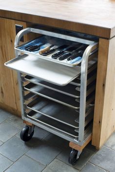 a kitchen island with trays on wheels holding utensils