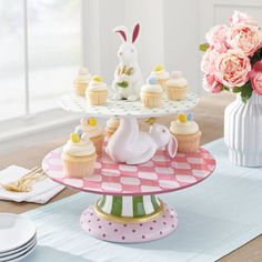 three tiered plates with cupcakes and flowers in vases on the table