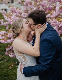 a bride and groom kissing in front of pink flowers