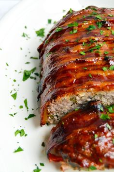 a meatloaf covered in sauce and garnished with parsley on a white plate