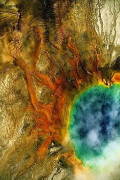 an aerial view of a large crater in the middle of nowhere, with blue and green water