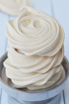 a metal bowl filled with white frosting on top of a table