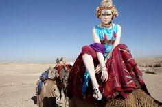 a woman is sitting on top of a camel in the middle of the desert with other people