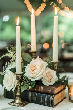 candles are lit on top of books and flowers