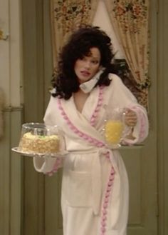 a woman in a bathrobe holding a cake on a tray