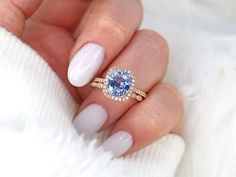 a woman's hand holding a ring with a blue stone