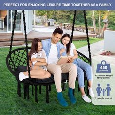 a man and two women sitting on a swing chair in the grass with their children