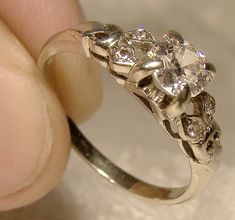 A vintage Art Deco era 18k white gold ring with diamonds circa 1930s.  This vintage size 5-1/4 diamond-set band had an independent gemmoligist appraisal in the amount of $1800 CAD (it is now missing), and the diamonds include a central antique brilliant cut .36 carat of SI-2 clarity (small girdle chip only visible under a 10X loupe, and it is noted in appraisal) with G colour along with four brilliant cut side diamonds (total .05 ct.).  This ring weighs 2.1 grams and It is 3/16" wide across the main diamond.   It is stamped 18 and it is in excellent condition with no chips, cracks, dents, bends, corrosion, losses, damage or repairs other than the chip.  All items are thoroughly and conservatively graded and all condition issues are noted;  all items are vintage or antique and may have slig Cheap Diamond Rings, Jewelry Appraisal, Diamonds Ring, Discount Jewelry, White Gold Diamond Rings, Jewelry Essentials, Jewelry Rings Diamond, Art Deco Era, White Gold Ring