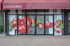 a store front with christmas decorations painted on the glass doors and windows, along with a red awning