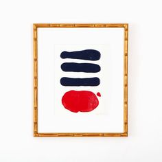 an abstract painting with blue, red and black colors in a gold frame on a white wall