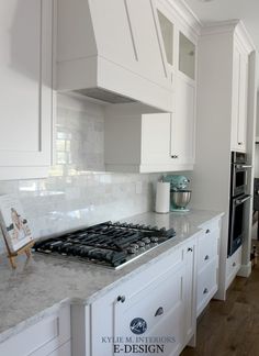 a kitchen with white cabinets and marble counter tops, along with an oven in the center